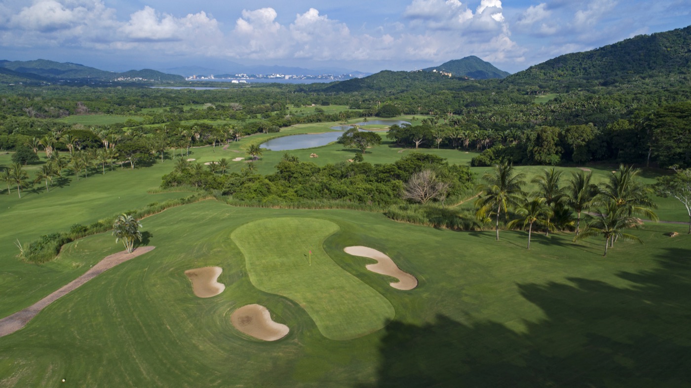 Vista aérea del campo de golf, con greens, lagos y palmeras